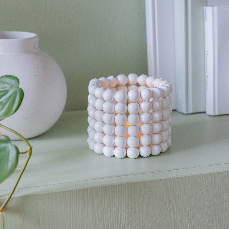 weißes Windlicht aus Holzkugeln auf Regal