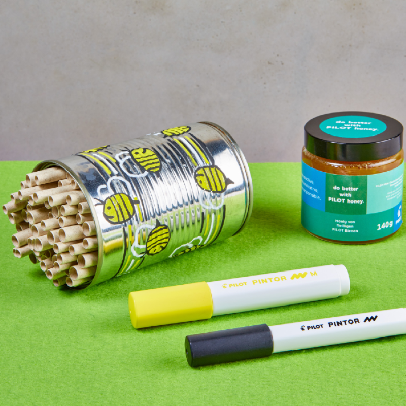 Dekoratives Insektenhotel mit Stiften und Honig