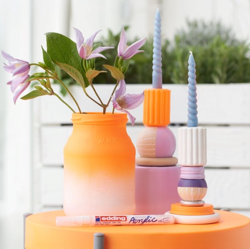 Zwei bunte Kerzenhalter mit Vase auf einem Tisch