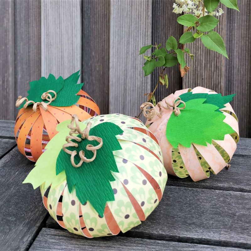 drei herbstlich bunte Kürbisse aus Papier auf dem Hlztisch