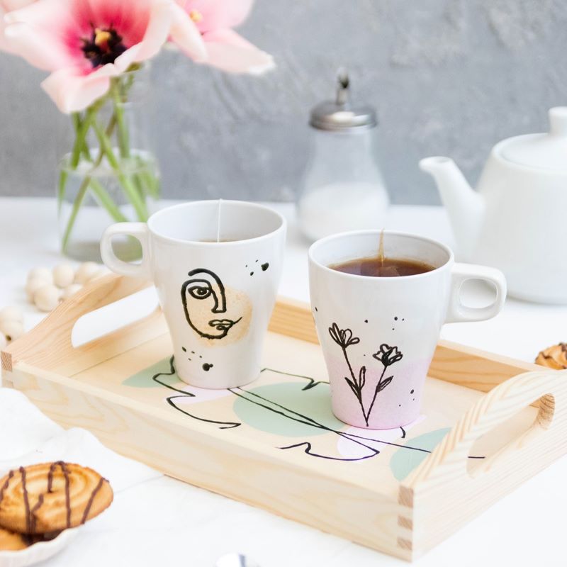 stilvolle Line Art Motive auf zwei Tassen und einem Holztablett